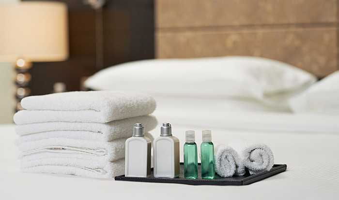 Hotel amenities and white towel on bed in hotel room