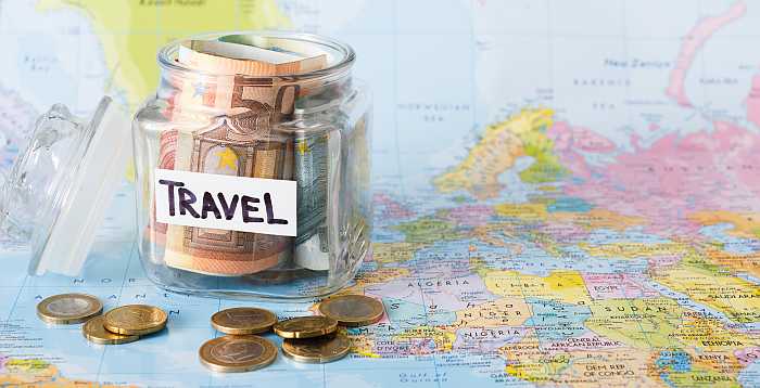 Budget travel concept - money in a jar sitting on top of a map (Photo: Envato)
