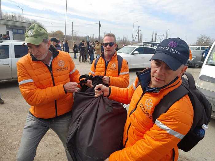 United Hatzalah volunteers assisting refugees carry their bags. (Photo: Volunteers of United Hatzalah)